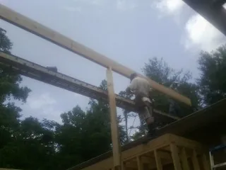 Carpenter setting a ridge beam over a new addition frame — Ice Dam Removal by Roofing Brothers in Milligan