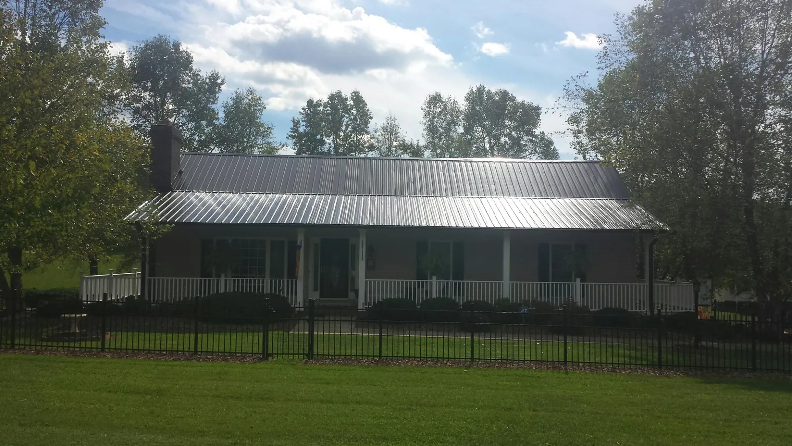 Gray metal roof on a brick ranch with a full width front porch — Gutter Guard Installation work by our crew in Milligan